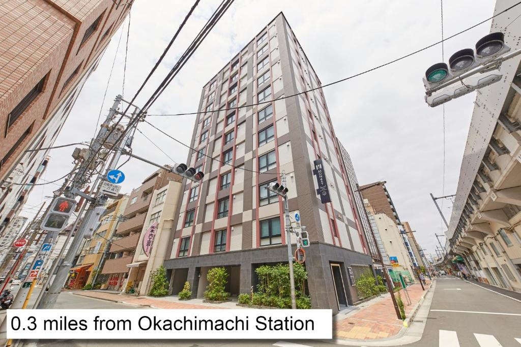 un edificio alto en una calle de la ciudad con un semáforo en MONday Apart Premium UENO OKACHIMACHI en Tokio