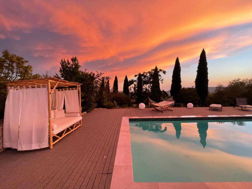 a swimming pool with a gazebo and a sunset at Le domaine des Petits Princes in Lorgues