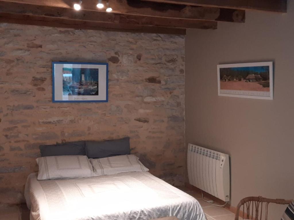 a bedroom with a bed and a stone wall at Gîte de l&#39;Ane Papillon-3 chb- piscine-jardin in Saint-Cirq-Souillaguet