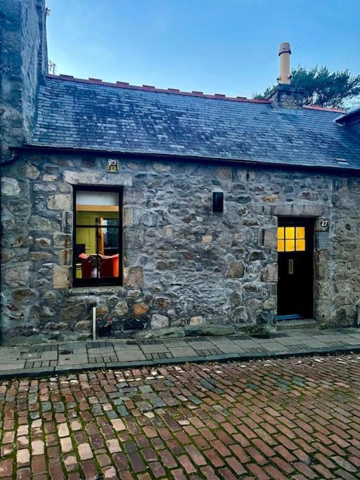 een stenen gebouw met twee ramen en een deur bij Historic Cottage in the Heart of Old Aberdeen. in Aberdeen