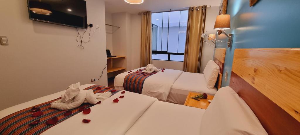 una camera d'albergo con due letti con cuori sui letti di HOTEL LUZ GARDEN a Machu Picchu