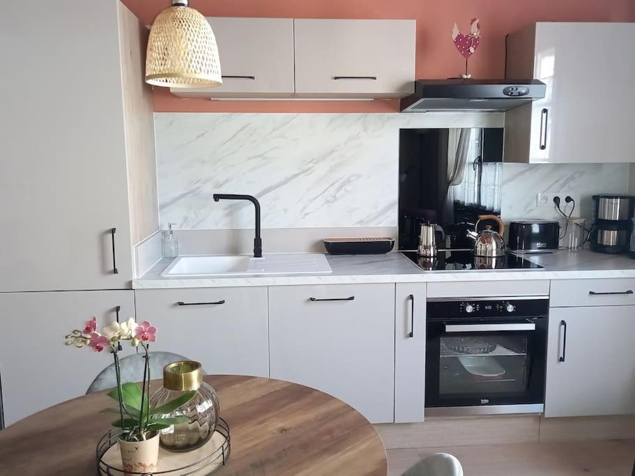 a kitchen with white cabinets and a table with a sink at S'gleina Gleck, in the heart of a wine city, Charmant Studio 1 pièce et 1 salle de bain in Kaysersberg
