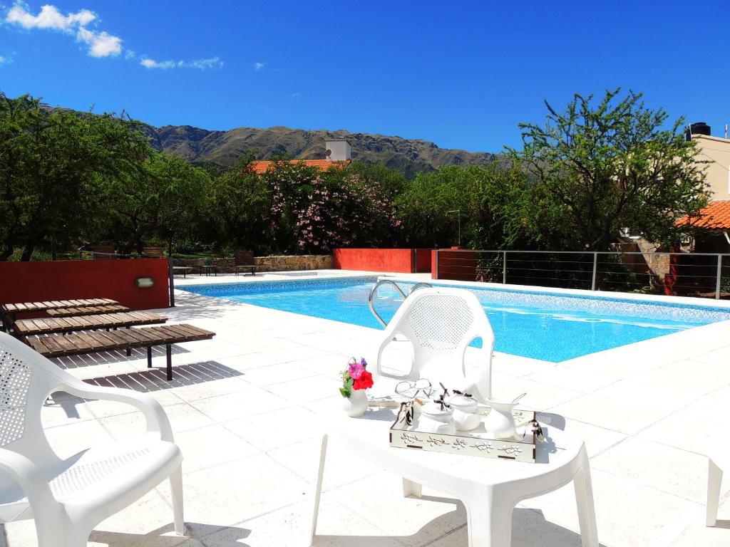 uma piscina com duas cadeiras brancas e uma mesa branca em Cabañas La Casa de Adriana em Merlo