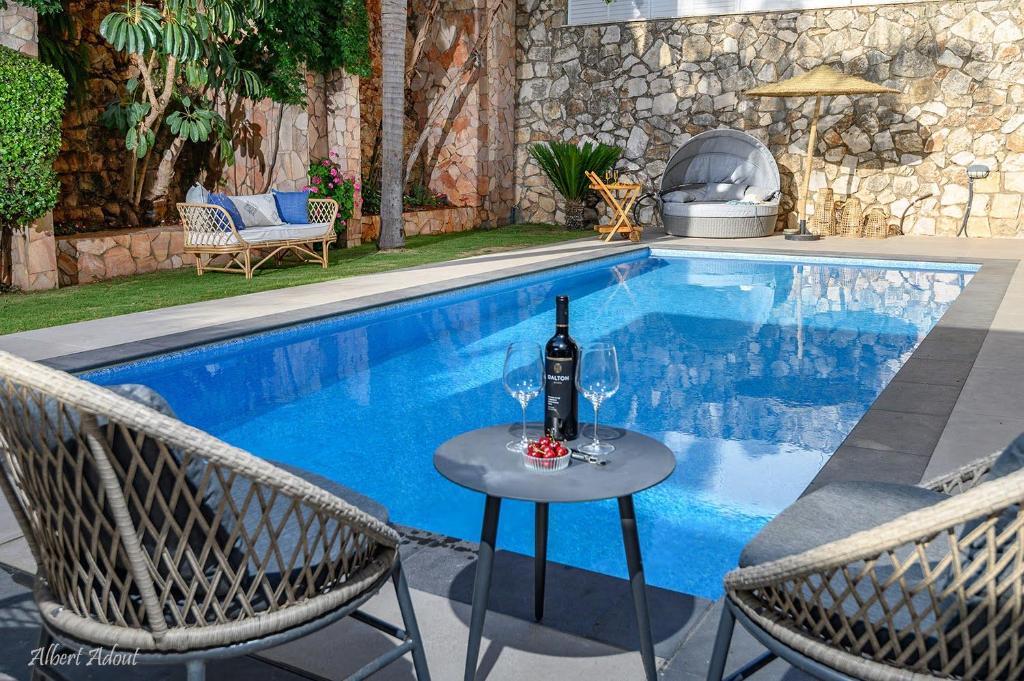 una botella de vino sentada en una mesa junto a la piscina en סוויטת הרמס- סוויטת פאר עם בריכת שחיה פרטית, en Safed