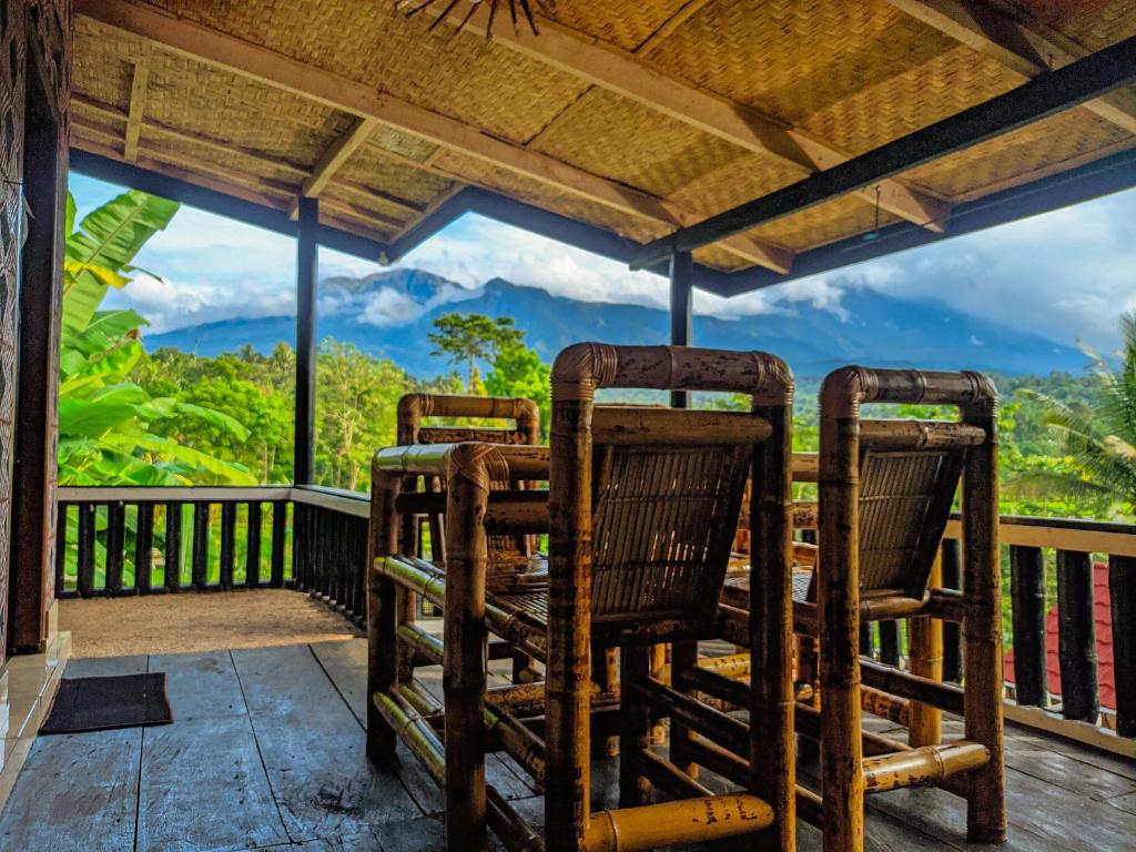 2 sillas en un porche con vistas a las montañas en Tetabatu Rice Terrace Homestay, en Tetebatu