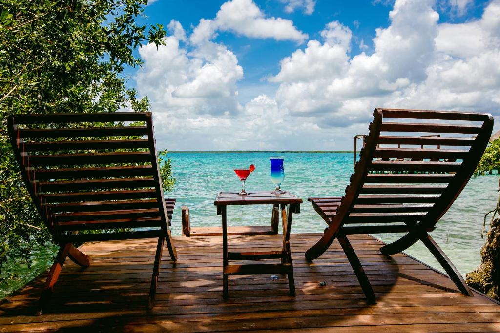 einen Tisch und zwei Stühle auf einer Terrasse am Meer in der Unterkunft Hotel Rancho Encantado in Bacalar