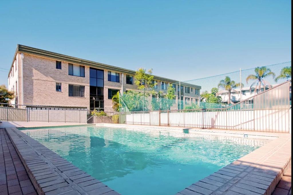 a swimming pool in front of a building at The Dunes 17 38 Marine Drive fabulous unit with pool tennis court in Fingal Bay