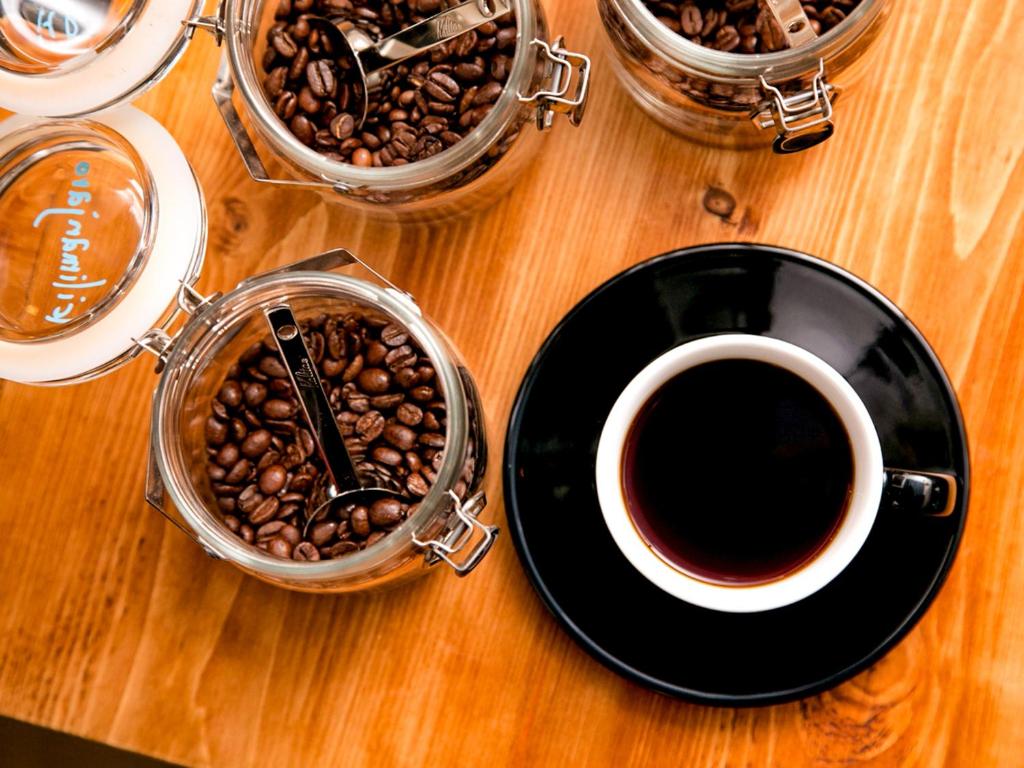 a table with a cup of coffee and a plate of coffee beans at Hotel Pacific Kanazawa in Kanazawa