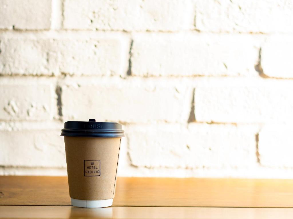 a coffee cup sitting on a table in front of a brick wall at Hotel Pacific Kanazawa in Kanazawa