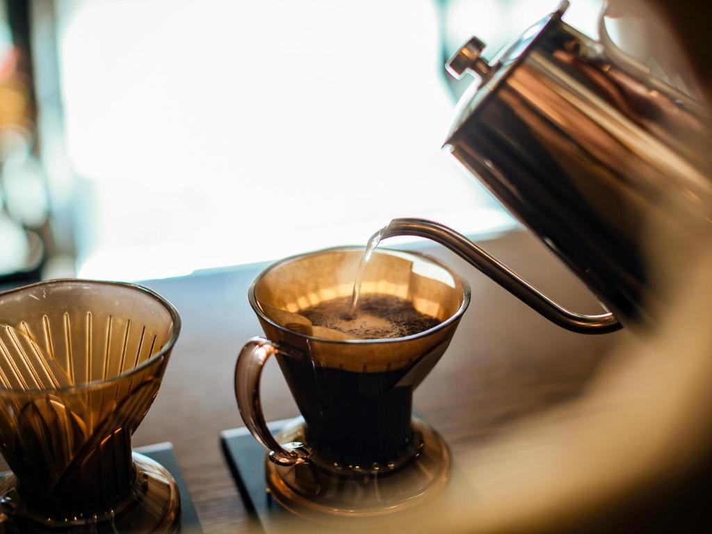 a cup of coffee sitting next to a tea kettle at Hotel Pacific Kanazawa in Kanazawa