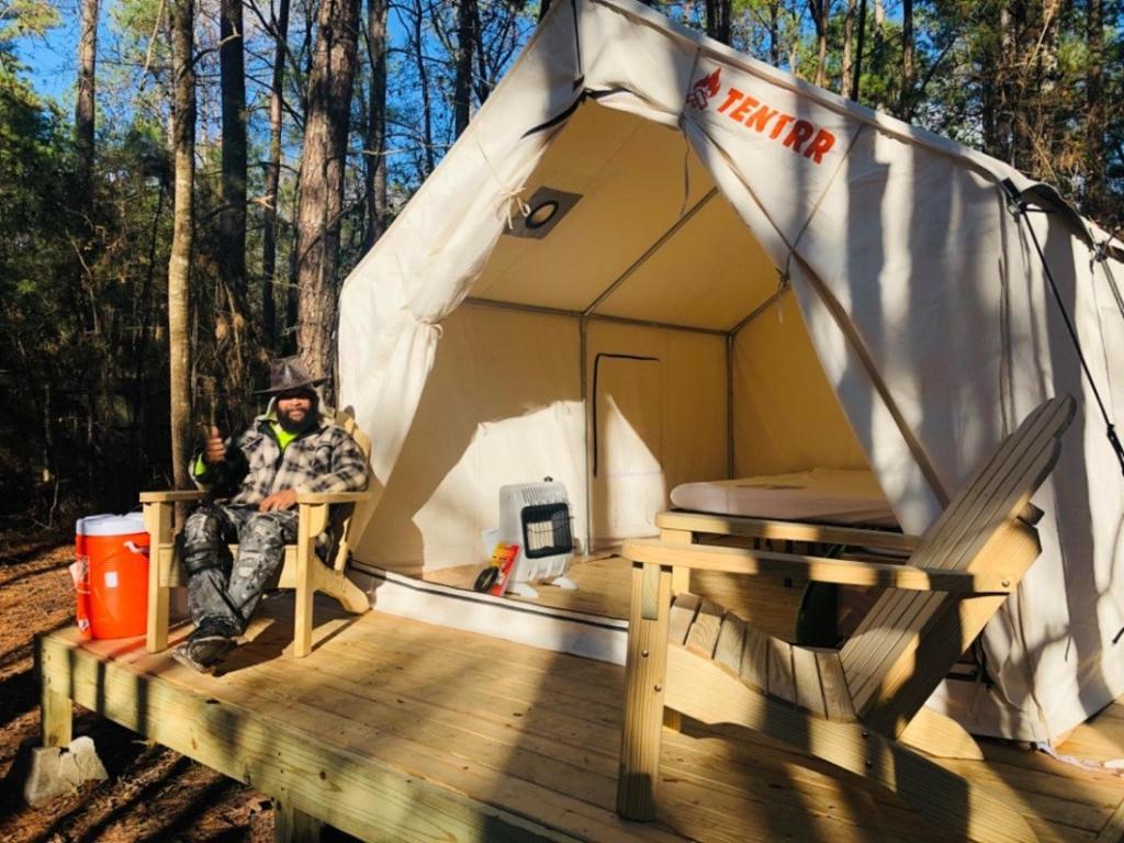 a man sitting in a tent on a wooden deck at Tentrr Signature Site - Exodus XX - A Private Lakefront Camp at Shabbat Retreat in Riverside