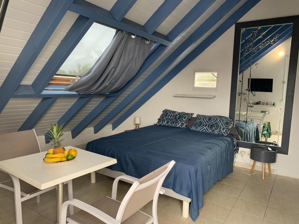 - une chambre avec un lit bleu, une table et des chaises dans l'établissement Paradise chez Nono, à Baie-Mahault
