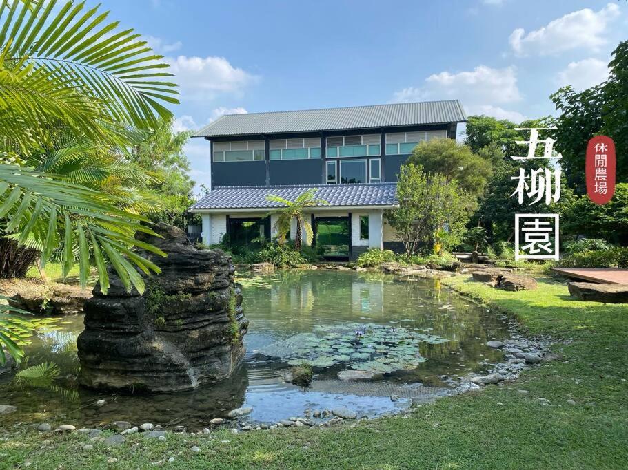 a house with a pond in front of a building at 五柳園休閒農場-嘉義市民宿001號 in Chiayi City