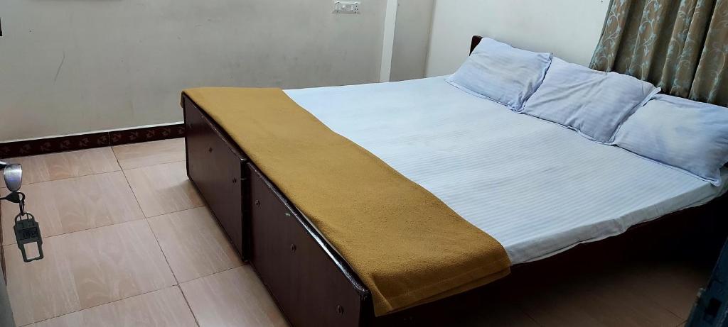 a bed with white sheets and a brown blanket on it at Vijaya Rooms in Tiruchchirāppalli