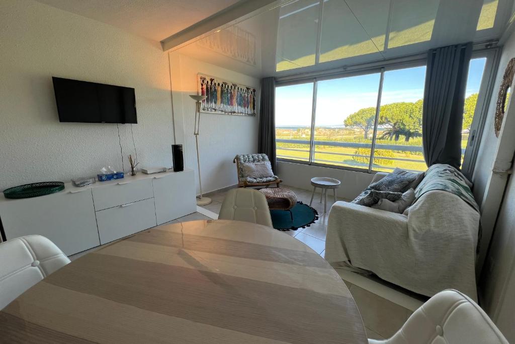 un soggiorno con un tavolo e una grande finestra di Le Studio de la Lagune studio cabine proche de la plage a Le Grau-du-Roi