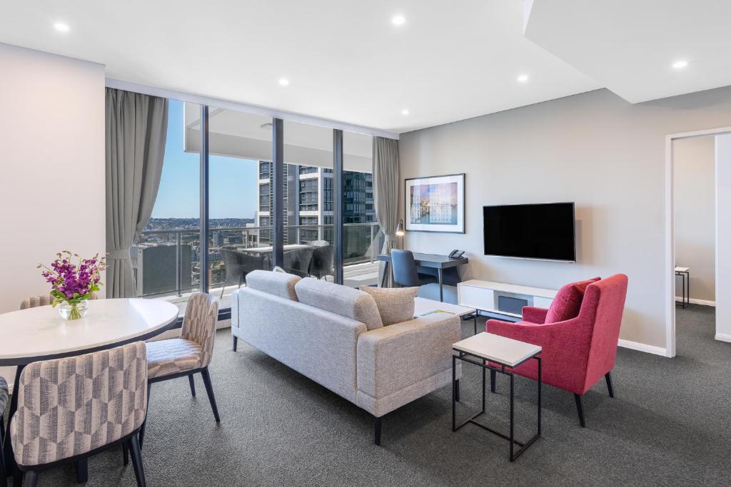 sala de estar con sofá, sillas y TV en Meriton Suites Kent Street, Sydney, en Sídney