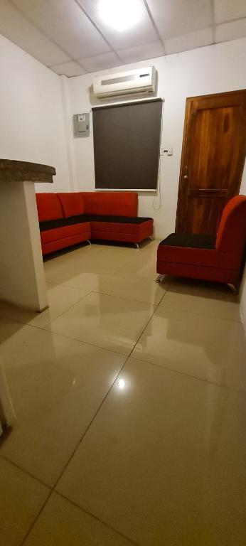 Habitación con TV de pantalla plana y sofá rojo. en SUITES FAMILIAR, en Guayaquil
