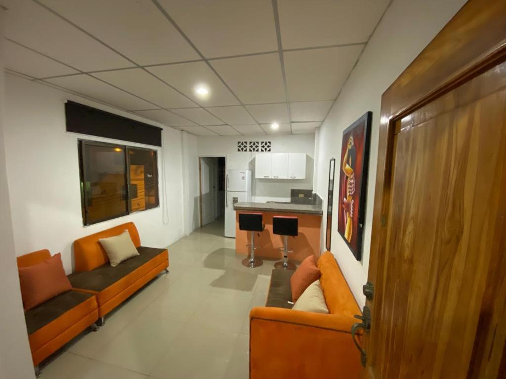 sala de estar con sofás naranjas y cocina en SUITES AMOBLADA, en Guayaquil