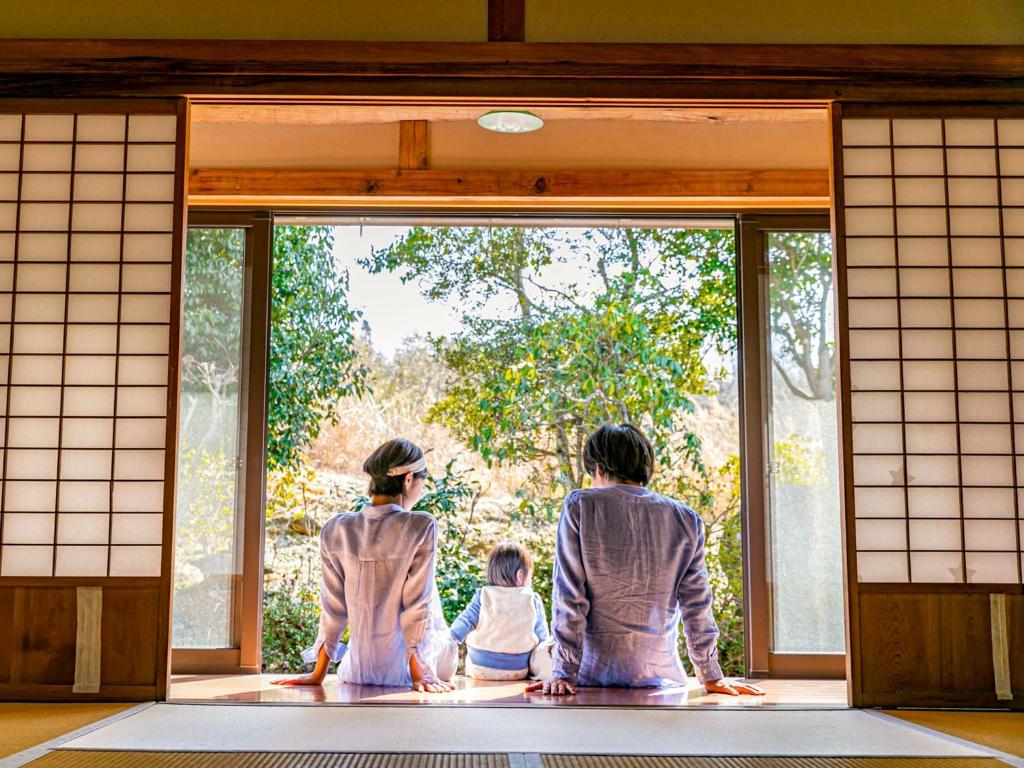 Due adulti e un bambino che guarda fuori da una porta di Irori no oyado zen - Vacation STAY 80209v a Mimasaka