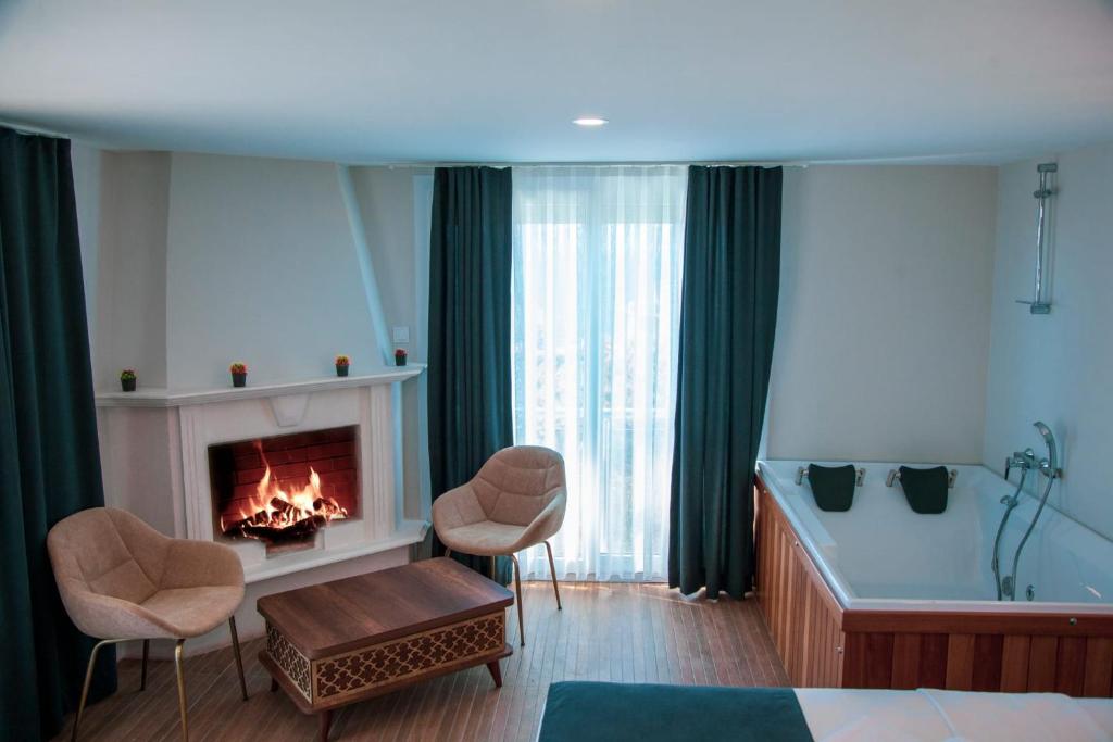 a room with a fireplace and two chairs and a tub at Aden Boutique Otel in Çeşme