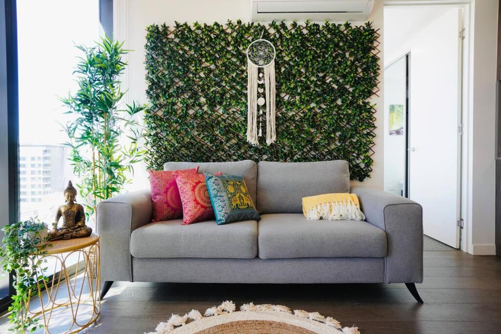 a couch in a living room with a green wall at City Zen Apartment-Gym-BBQ in Adelaide