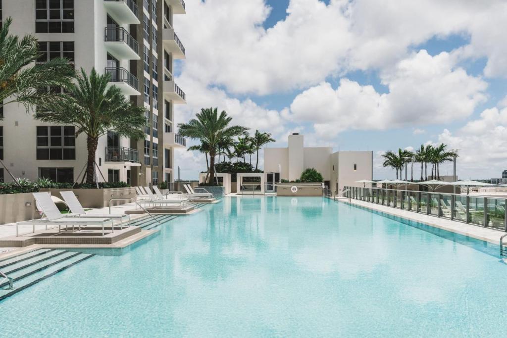 a large swimming pool with chairs and palm trees at Tucker at Palmer Dadeland Miami in Miami