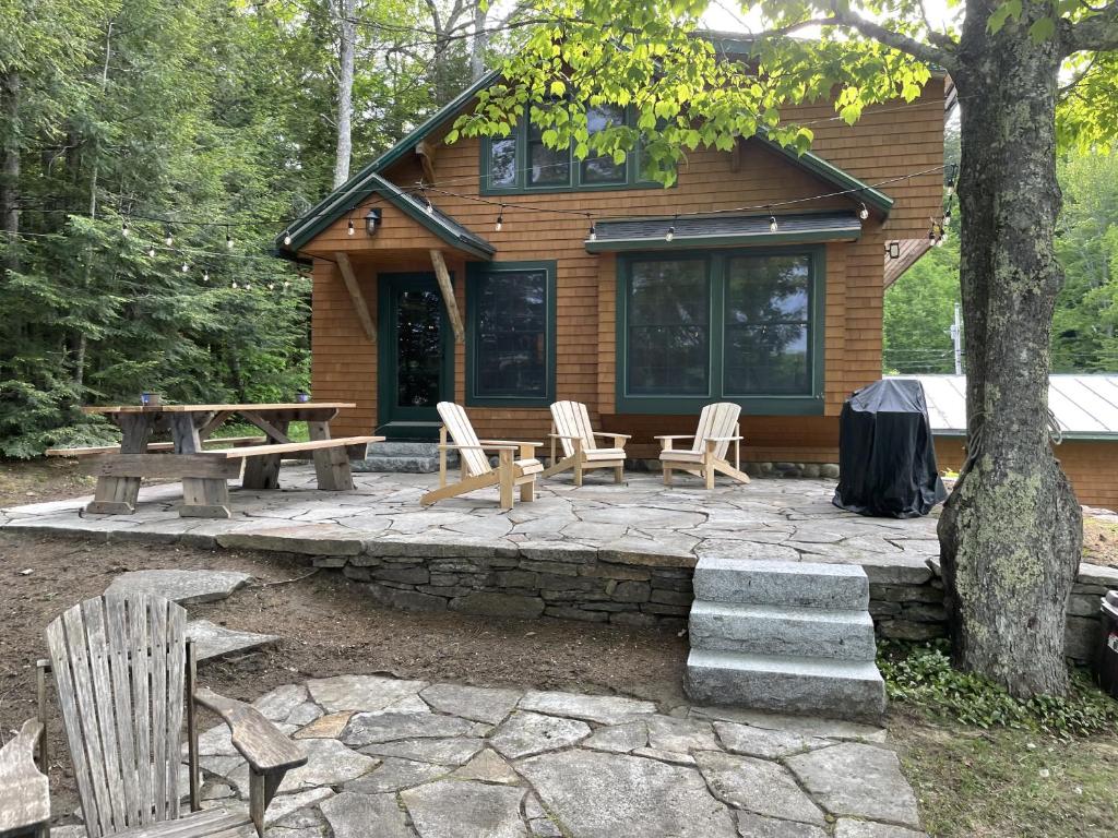 a log cabin with a picnic table and chairs in front of it at Great Pond House in Belgrade