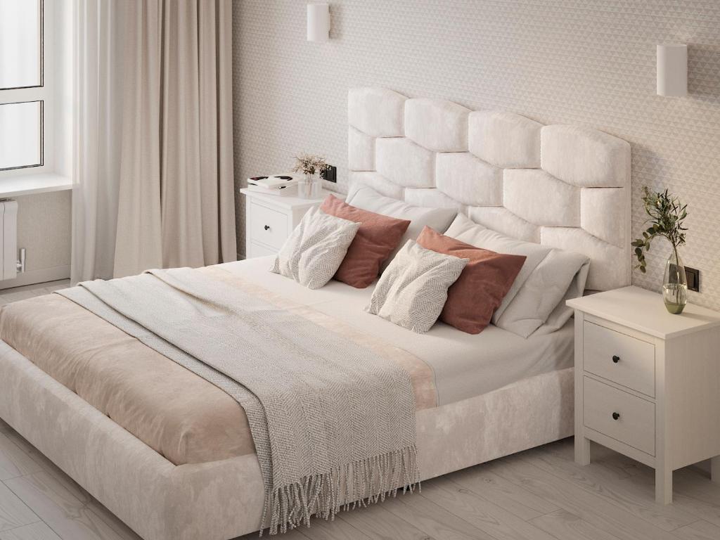 ein weißes Schlafzimmer mit einem großen weißen Bett mit Kissen in der Unterkunft Дизайнерська сучасна квартира in Luzk