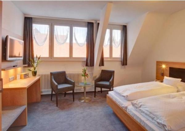 a bedroom with a bed and two chairs and a desk at Hotel Bären in Villingen-Schwenningen