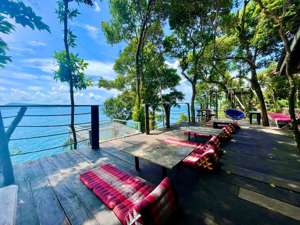 a group of benches sitting on a deck overlooking the water at The Cliff Hostel, M'Pay Bay in Koh Rong Sanloem