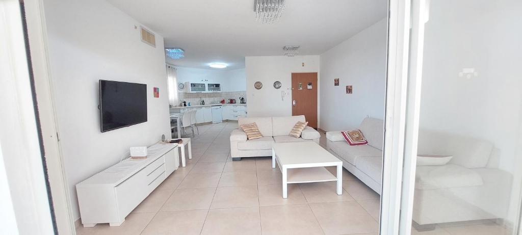 sala de estar blanca con sofá y TV en Sitrin apartment Leonardo Hotel Area Ashdod, en Ashdod