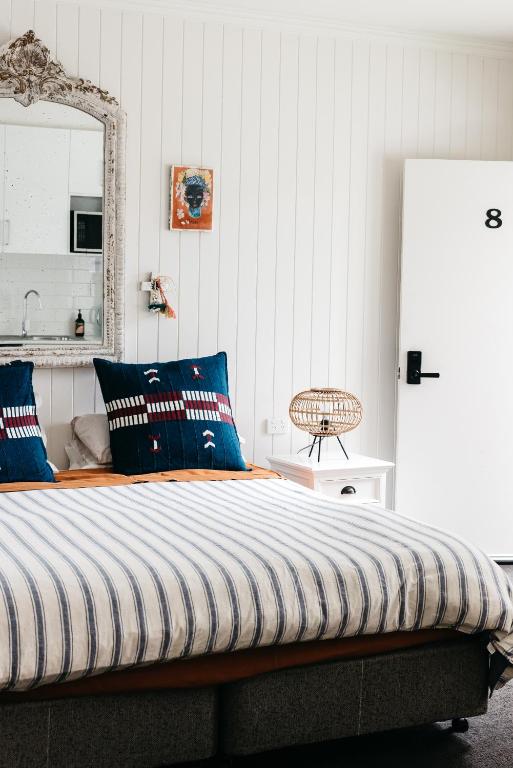 a bedroom with a bed with blue pillows and a mirror at Anchor Geelong in Geelong