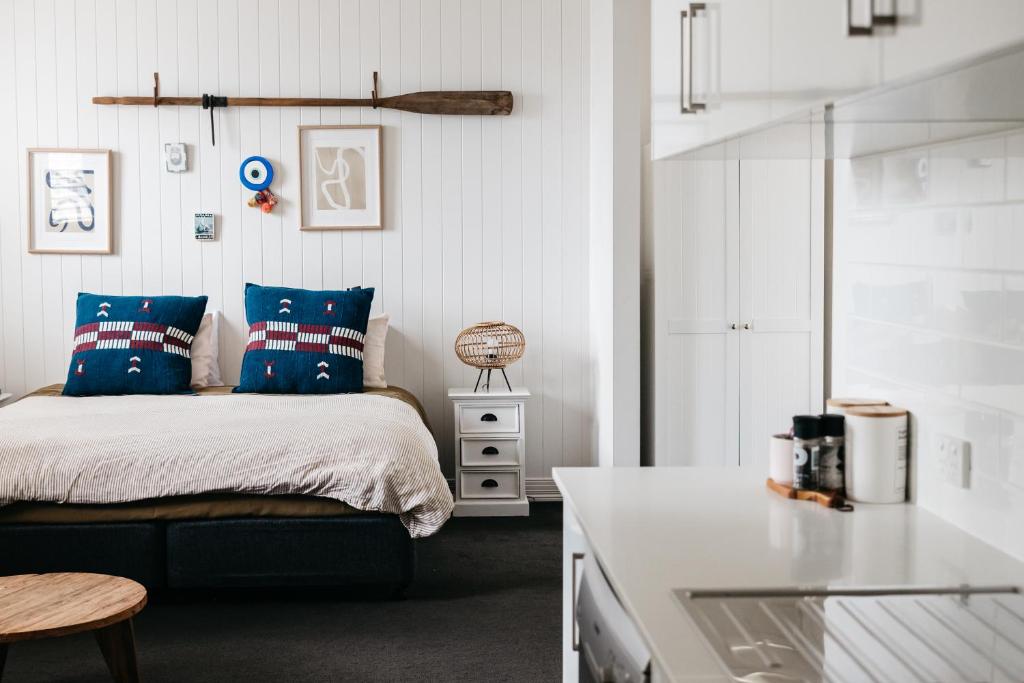 a bedroom with a bed with blue pillows and a kitchen at Anchor Geelong in Geelong