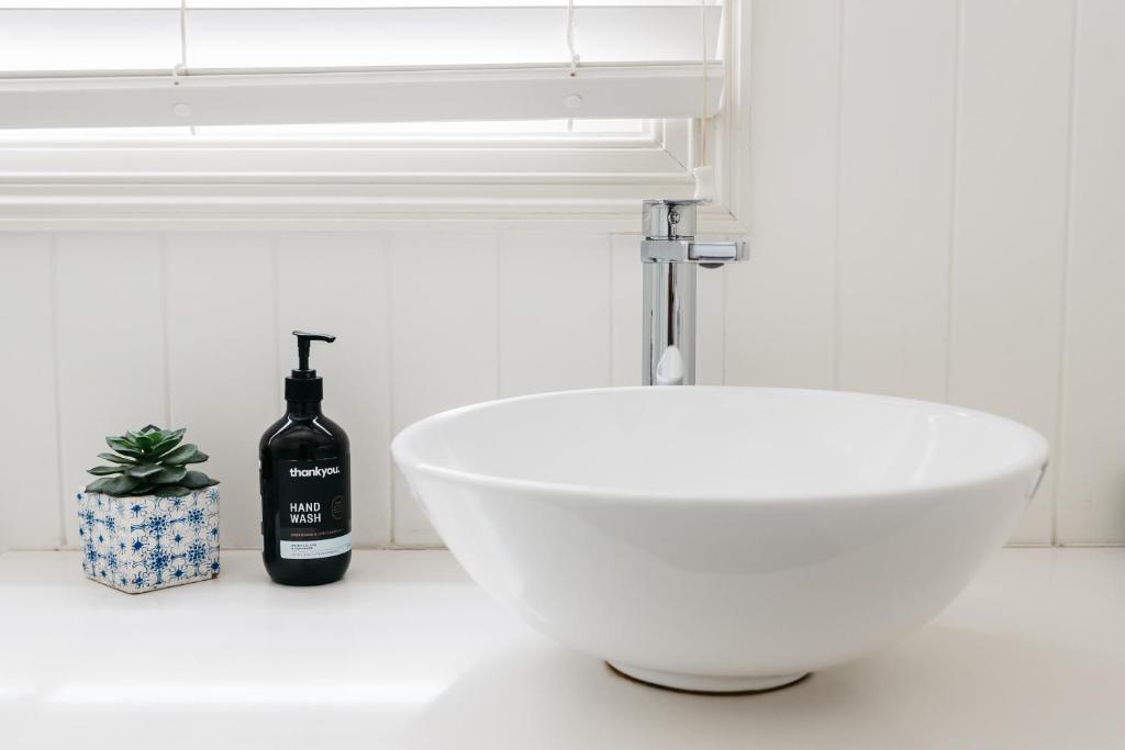 a white bathroom with a white sink and a window at Anchor Geelong in Geelong