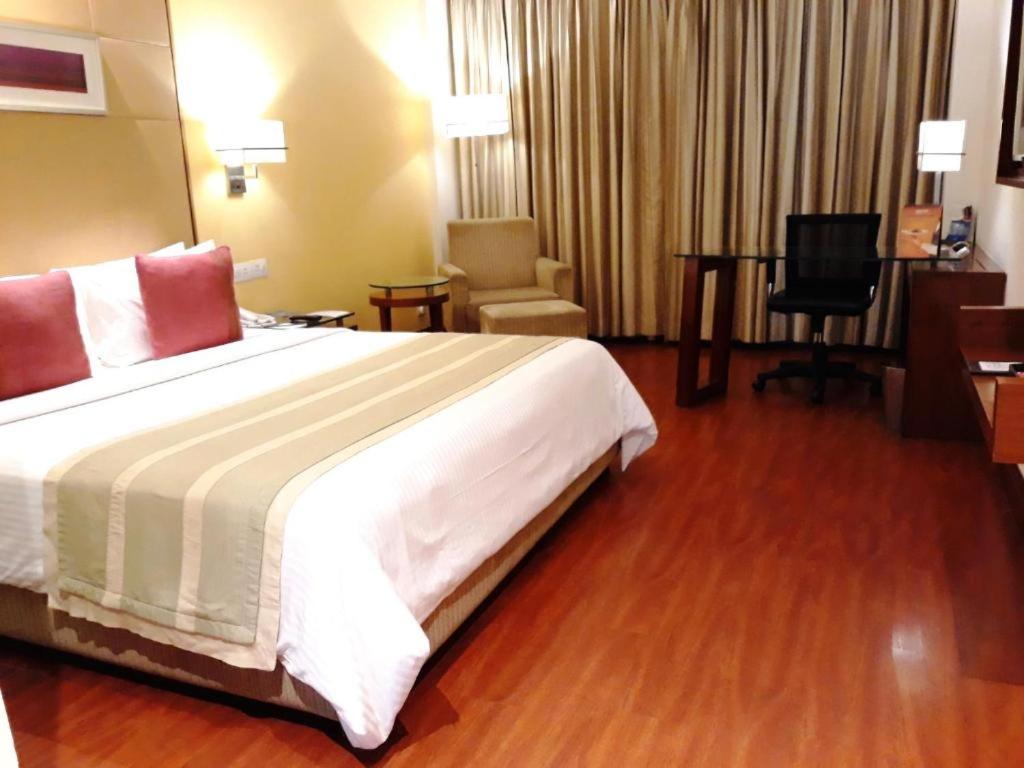 Habitación de hotel con cama grande y escritorio. en Park Inn Gurgaon, en Gurgaon