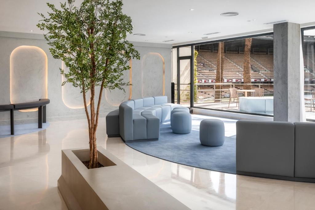 eine Lobby mit einem Baum, Stühlen und einem Tisch in der Unterkunft B&B HOTEL Jerez in Jerez de la Frontera