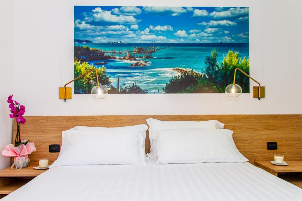 una camera con un letto bianco e una foto dell'oceano di Residence al Palace a Vasto