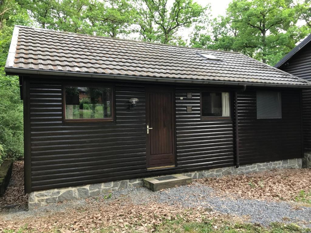 a black cabin with a door and a window at Aux Bons Vivants in Heure