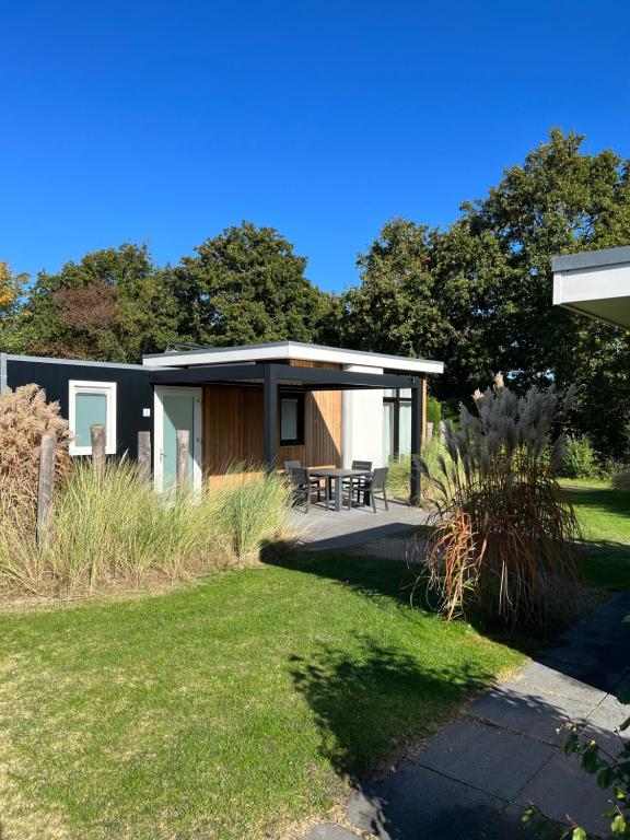 een modern huis met een patio en gras bij Vakantiepark Schouwenduin in Burgh Haamstede
