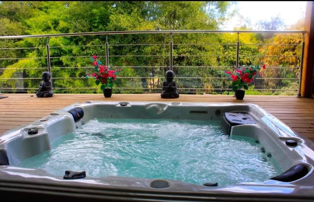 a hot tub on a deck with flowers at Gite correze spa jaccuzi massage in Saint-Germain-les-Vergnes