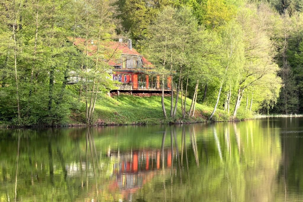 a house sitting on the side of a river at Ferienwohnungen & Campingfässer am Kunstteich in Wettelrode