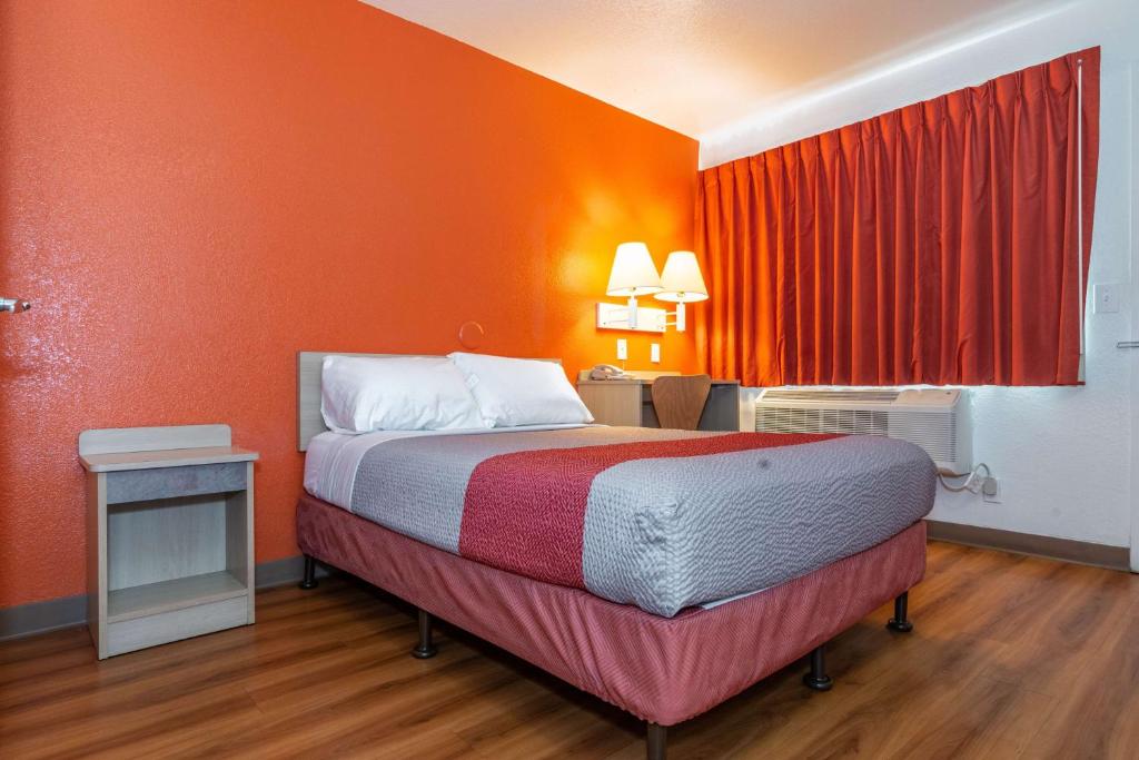 a bed in a room with an orange wall at Motel 6-Palm Springs, CA - East - Palm Canyon in Palm Springs