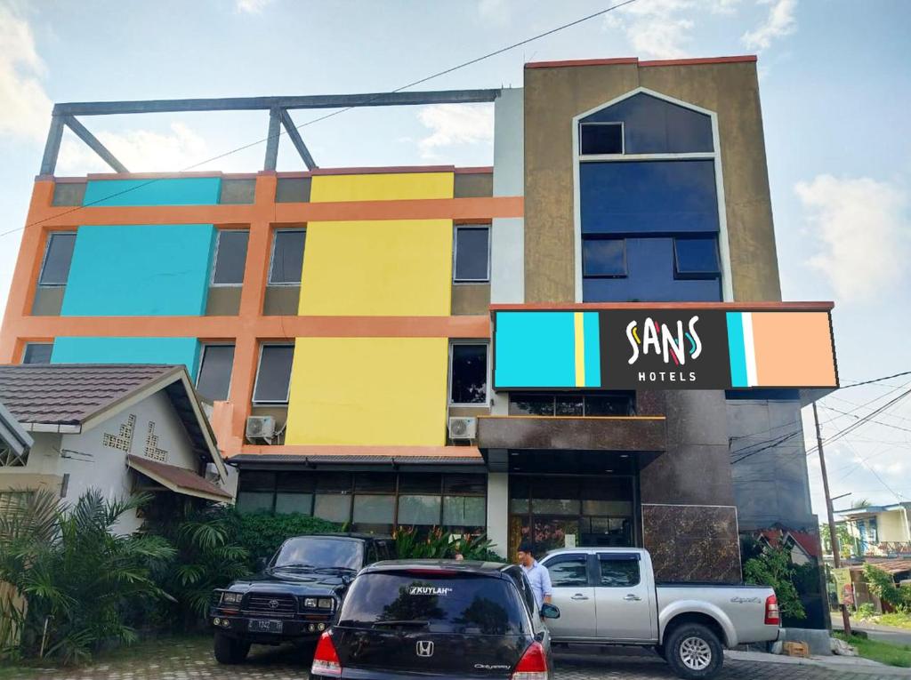 budynek z samochodami zaparkowanymi przed nim w obiekcie Sans Hotel Havila Bengkulu w mieście Bengkulu