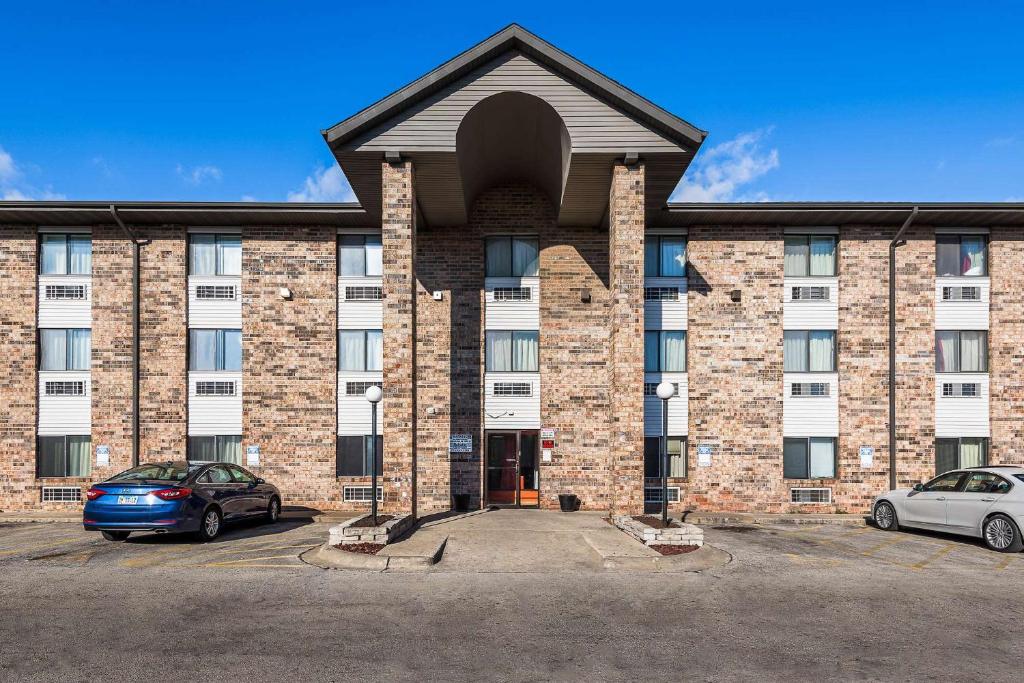 a large brick building with two cars parked in a parking lot at Motel 6-Bridgeview, IL in Bridgeview