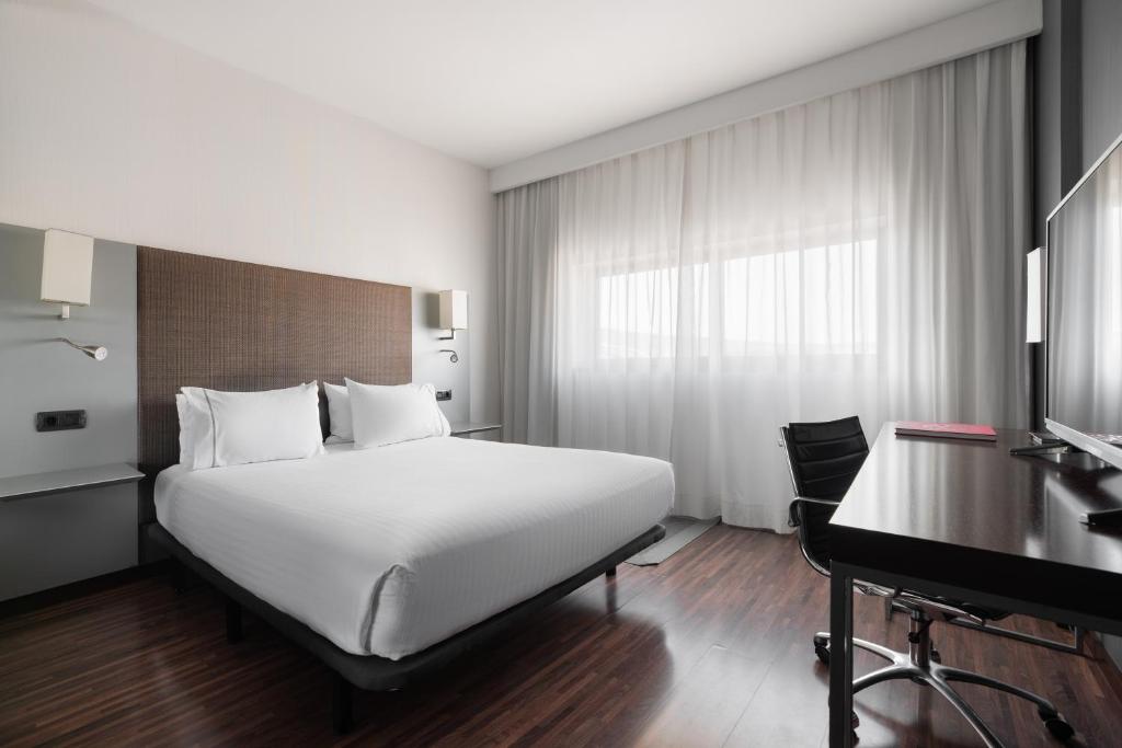 a bedroom with a large white bed and a desk at Exe Zizur Pamplona in Zizur Mayor