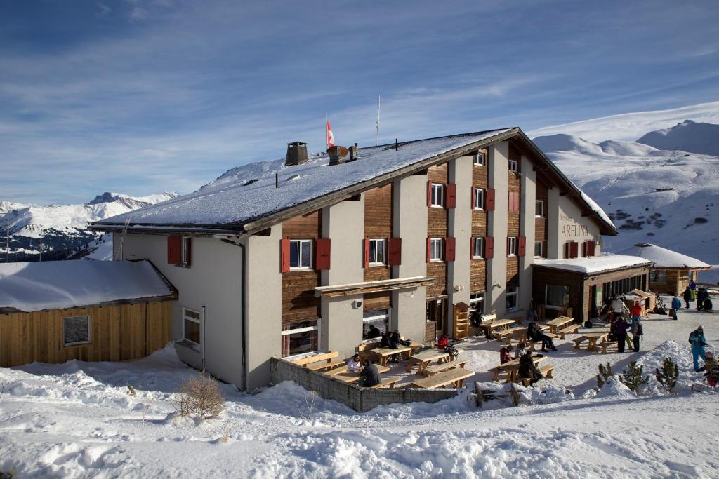 ein großes Gebäude im Schnee mit Leuten draußen in der Unterkunft Heuberge in Fideris Dorf