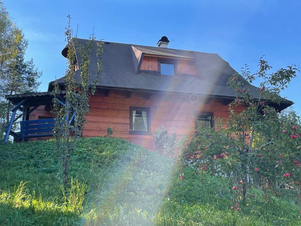 a house on a hill with the sun shining on it at Horská chalupa Pluskovjanka in Velké Karlovice