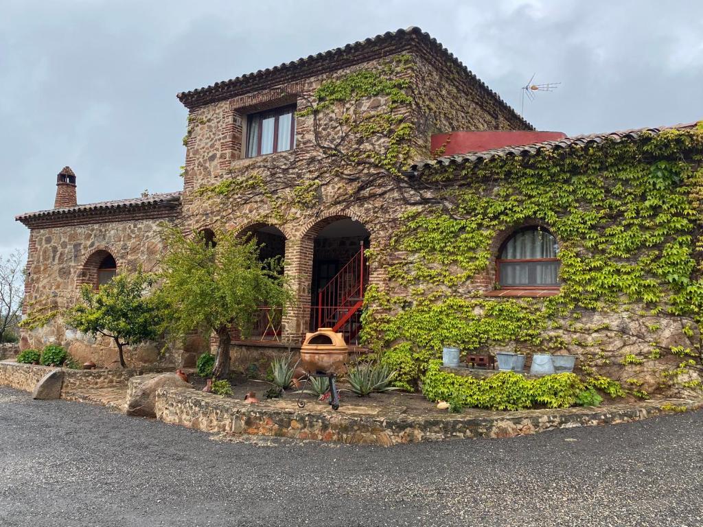 a stone house with ivy on the side of it at Casas Rurales Monasterio de Rocamador in Almendral