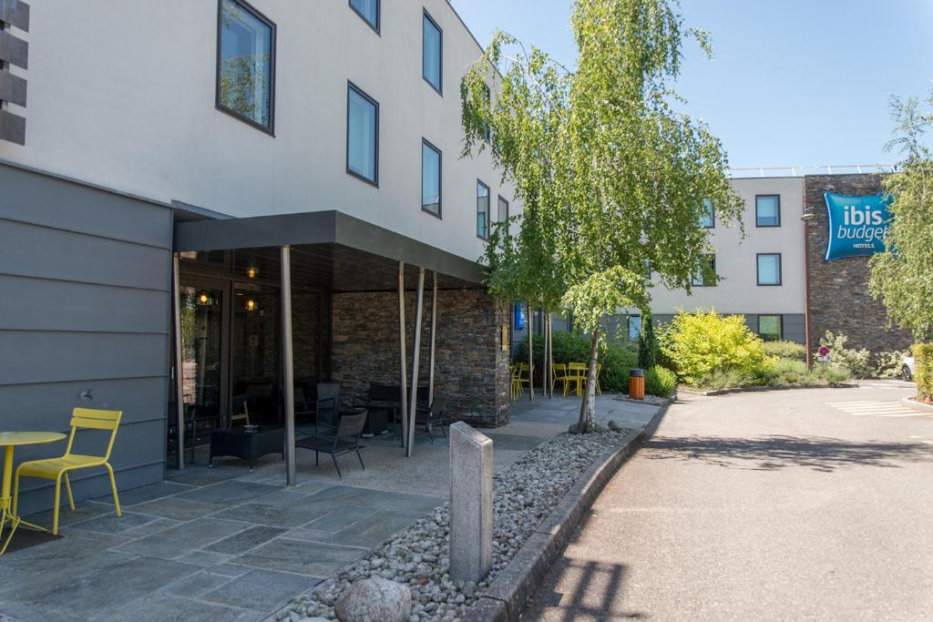 un bâtiment avec une table et des chaises devant lui dans l'établissement Ibis Budget Archamps Porte de Genève, à Archamps