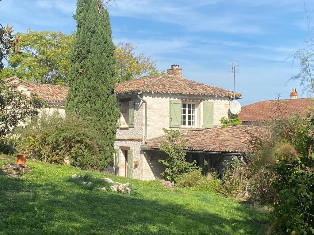 uma casa com uma grande árvore num quintal em La Caza du quercy em Cazes-Mondenard